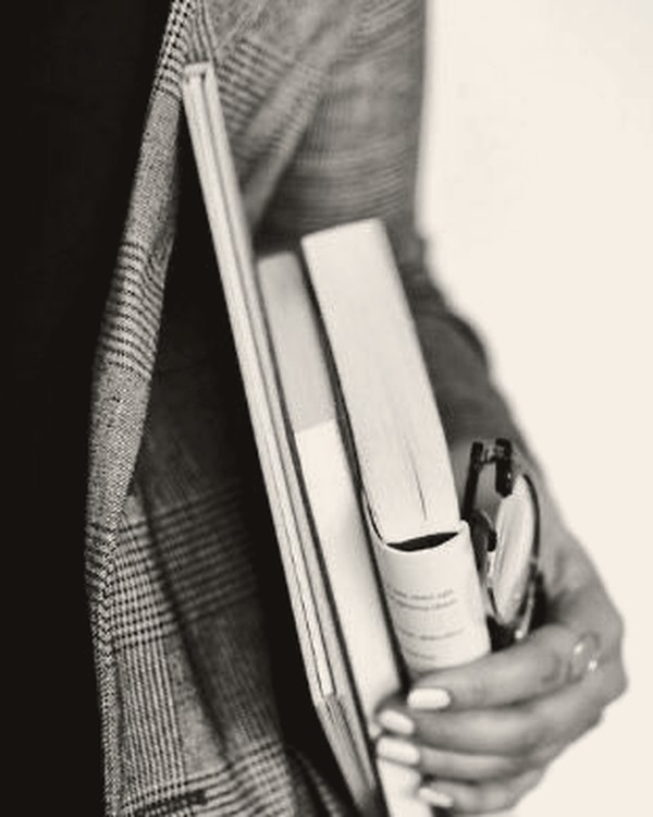 Books and glasses held against a tailored jacket