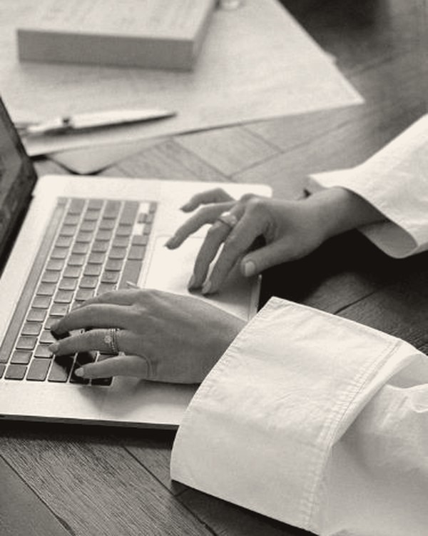 Hands on a laptop at a wood table